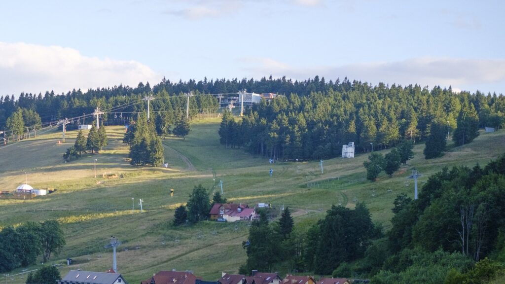 Zieleniec poza sezonem: zielone stoki z kolejami linowymi nad zabudową miejscowości